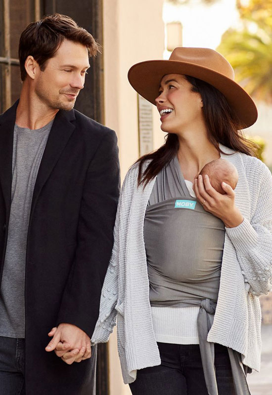 Papa und Mama tragen ihr Baby im Moby Classic Stone