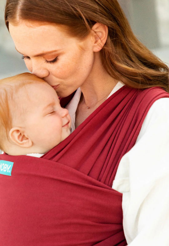 Mama küsst im elastischen Moby Tuch Ruby ihr Baby